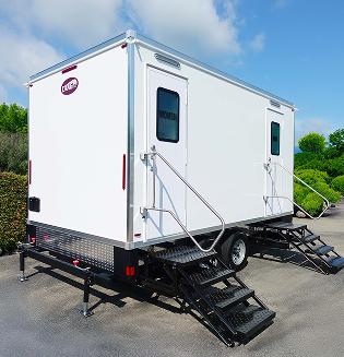Exterior view of a luxury restroom trailer in front of a green hedge