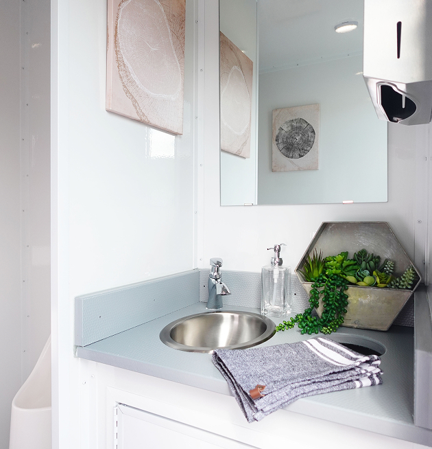 Interior view of luxury restroom with running water sink and gray linen towel