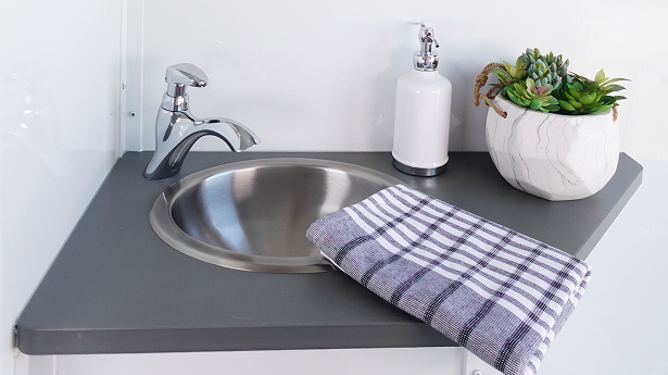 close up of a restroom trailer sink with a running water sink and decor items